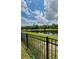 Scenic water view with lush greenery, calm lake, and blue sky, framed by a black metal fence at 11055 Belle Haven Dr, New Port Richey, FL 34654