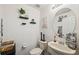 Charming half-bathroom featuring a decorative mirror, wall shelves, and pedestal sink at 1108 Blackwater Dr, Wesley Chapel, FL 33543