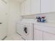 Bright laundry room featuring white cabinets and modern washer and dryer at 11158 Heathrow Ave, Spring Hill, FL 34609