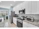Modern kitchen with white cabinets, stainless steel appliances, granite countertops and plenty of natural light via window shutters at 11308 Mollymawk Ct, New Port Richey, FL 34654