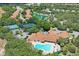 High aerial view of the community clubhouse, pool, tennis courts, scenic pond, and surrounding neighborhood at 11389 Mcnally Dr, Spring Hill, FL 34609