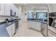 Kitchen area showing stainless steel appliances, view of the living room, and white cabinetry at 11389 Mcnally Dr, Spring Hill, FL 34609