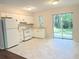 Bright kitchen features white cabinetry, appliances, and tile flooring with sliding glass doors to the outdoors at 11751 Key Lime Dr, New Port Richey, FL 34654
