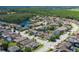 Aerial view of a community with a pond surrounded by lush green trees and well-maintained homes at 12750 Tikal Way, Trinity, FL 34655