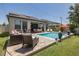 Spacious backyard featuring a pool, patio seating, an outdoor dining area, and green lawn at 12750 Tikal Way, Trinity, FL 34655
