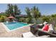 Serene backyard featuring a pool with in-pool seating, a fire pit lounge, and lush landscaping at 12750 Tikal Way, Trinity, FL 34655