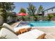 Backyard pool with in-pool loungers and red umbrella, surrounded by patio furniture and lush landscaping at 12750 Tikal Way, Trinity, FL 34655