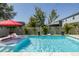 Sparkling swimming pool with in-pool seating, red umbrella and lush landscaping at 12750 Tikal Way, Trinity, FL 34655