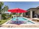 Beautiful backyard pool with in-pool loungers, red umbrella, and patio dining area at 12750 Tikal Way, Trinity, FL 34655
