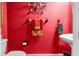 Bathroom with a red accent wall, toilet, and pedestal sink at 13155 Cori Loop, Spring Hill, FL 34609