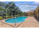 A serene screened-in pool with brick pavers and a lush backyard view, ideal for relaxation and entertaining at 13155 Cori Loop, Spring Hill, FL 34609