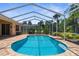 A stunning view of the pool featuring a screened enclosure, brick pavers and outdoor seating at 13155 Cori Loop, Spring Hill, FL 34609
