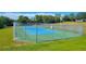 Outdoor fenced tennis court surrounded by green grass on a sunny day at 13155 Cori Loop, Spring Hill, FL 34609