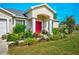 Close-up of a home's front entrance, highlighting the vibrant garden and red front door at 13317 Pinellas Ave, Spring Hill, FL 34609