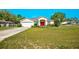 Charming home featuring a well-manicured lawn, colorful garden, and a striking red front door at 13317 Pinellas Ave, Spring Hill, FL 34609