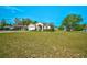 Charming home featuring a well-manicured lawn, colorful garden, and a striking red front door at 13317 Pinellas Ave, Spring Hill, FL 34609