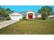 Charming home featuring a well-manicured lawn, colorful garden, and a striking red front door at 13317 Pinellas Ave, Spring Hill, FL 34609