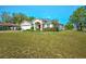 Charming home featuring a well-manicured lawn, colorful garden, and a striking red front door at 13317 Pinellas Ave, Spring Hill, FL 34609