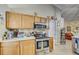 Well-lit kitchen featuring wooden cabinets, stainless steel appliances, and access to the living room at 13317 Pinellas Ave, Spring Hill, FL 34609