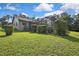 Wide shot of backyard with lush lawn, foliage, and view of screened pool enclosure at 13460 Pia Ct, Spring Hill, FL 34609