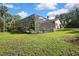 Home exterior view featuring a screened-in pool enclosure and lush green lawn at 13460 Pia Ct, Spring Hill, FL 34609