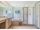 Well-lit bathroom features a soaking tub, glass-enclosed shower, single sink vanity, and neutral decor, providing comfort and style at 1407 Hickory Moss Pl, Trinity, FL 34655