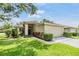 Inviting single-story home featuring lush green lawn, colorful landscaping, and an attached two-car garage at 1407 Hickory Moss Pl, Trinity, FL 34655