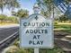 Humorous sign reads Caution Adults at Play for a fun, active community setting at 1407 Hickory Moss Pl, Trinity, FL 34655