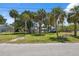 A street view shows a waterfront property with many mature palm trees in the yard under a blue sky at 14220 Hendry Ct, Hudson, FL 34667