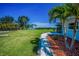 Beautiful backyard with manicured lawn, palm trees, and waterfront views at 1620 Sea Breeze Dr, Tarpon Springs, FL 34689