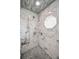 This stylish shower features marble tiling, built-in niches, and a unique octagon window at 1620 Sea Breeze Dr, Tarpon Springs, FL 34689