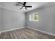 Empty bedroom featuring gray walls, luxury vinyl plank flooring, modern ceiling fan, and bright window at 2866 Thistle N Ct, Palm Harbor, FL 34684