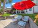 Relaxing patio with wicker furniture and a red umbrella, perfect for enjoying the outdoors at 4292 Tahiti Dr, Hernando Beach, FL 34607
