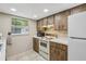 Bright kitchen featuring wooden cabinets, white appliances, and a window for natural light at 4424 Whitetail Ln, New Port Richey, FL 34653