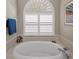 Close-up of a soaking tub with tiled surround and window with privacy shutters at 4485 Gevalia Dr, Brooksville, FL 34604