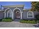 Elegant front entrance with double doors, white pillars, arched windows, and vibrant landscaping at 4485 Gevalia Dr, Brooksville, FL 34604
