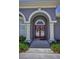 Close-up of the elegant front entrance, featuring double doors and white pillars, surrounded by manicured landscaping at 4485 Gevalia Dr, Brooksville, FL 34604