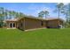 Spacious backyard featuring a lush green lawn and the exterior of a tan home with a neutral roof at 4960 Hidden Knob Trl, Spring Hill, FL 34609