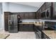 Modern kitchen with stainless steel appliances, granite countertops, and dark wood cabinetry at 4960 Hidden Knob Trl, Spring Hill, FL 34609