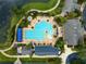 Aerial view of community pool, deck, and lounge chairs surrounded by verdant landscaping and a winding trail at 5005 Southern Valley Loop, Brooksville, FL 34601