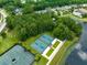 Aerial view of the community's well-maintained tennis and pickleball courts nestled among lush greenery and a pond at 5005 Southern Valley Loop, Brooksville, FL 34601