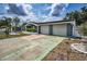 A long driveway leads to a charming blue home featuring a two-car garage and lush landscaping at 5132 Flora Ave, Holiday, FL 34690