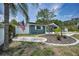Charming single-story home featuring lush landscaping, a privacy fence, and mature palm trees at 5132 Flora Ave, Holiday, FL 34690