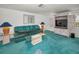 Bright living room featuring a statement wall unit, turquoise carpet, and comfortable seating at 5132 Flora Ave, Holiday, FL 34690