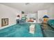 Open-concept living area with turquoise carpet, comfortable seating, and vintage lamps at 5132 Flora Ave, Holiday, FL 34690