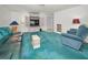 Cozy living room with vintage-style blue carpet, decorative furnishings, and natural light at 5132 Flora Ave, Holiday, FL 34690