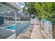 Walkway shows screened pool, fence, and privacy landscaping at 5132 Flora Ave, Holiday, FL 34690