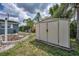 Outdoor shed with double door entry and adjacent flowerbed with a blue house in background at 5132 Flora Ave, Holiday, FL 34690