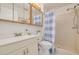 Clean bathroom features a shower with blue striped curtain, white vanity, and ample lighting at 6508 Tina Dr # 14, New Port Richey, FL 34653