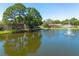 Wide pond view reflecting the community's landscape, pool, and residences under a clear sky with a fountain at 6508 Tina Dr # 14, New Port Richey, FL 34653